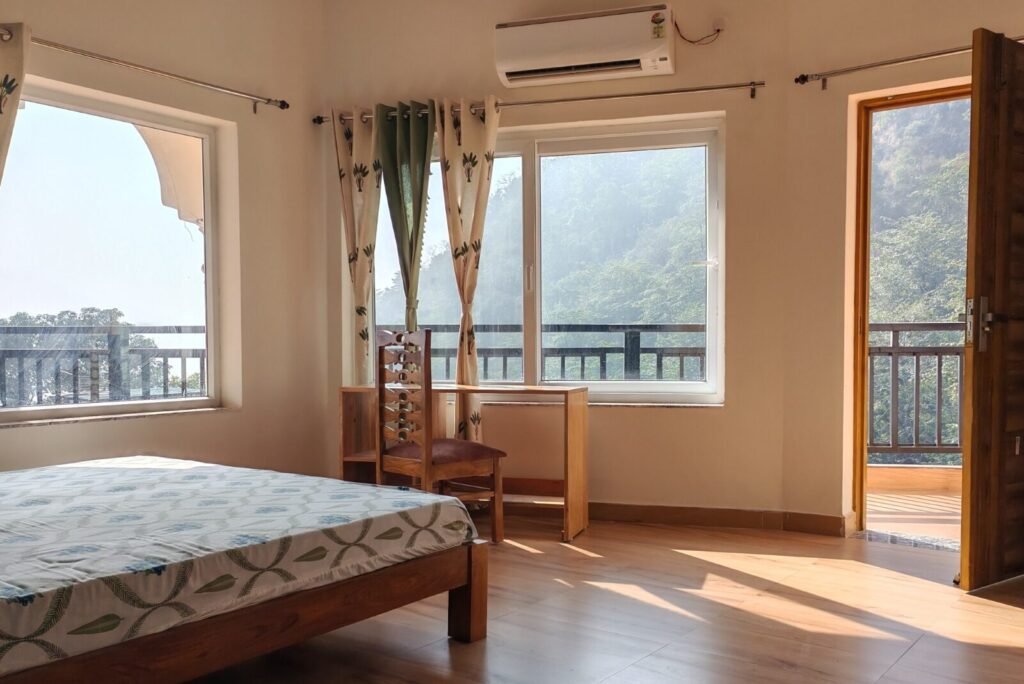 Interior of the Mountain View Room with bed, desk, large windows and mountain scenery