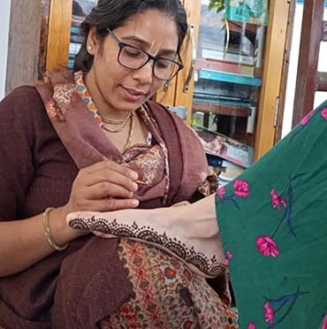 Miss Anju applying a traditional henna design to a guest's hand